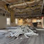 Lane Road 1st floor building interior during demolition with exposed ceiling, insulation, construction debris, and piled metal framing.